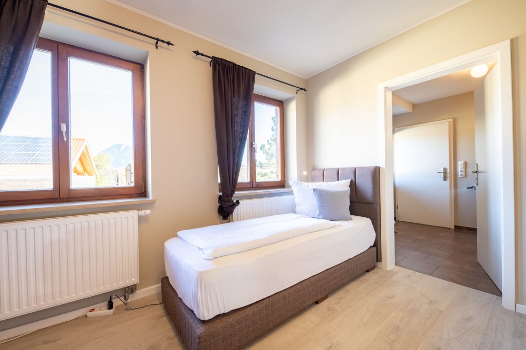 Einzelbett mit Tür zum Flur in Ferienwohnung in Garmisch-Partenkirchen