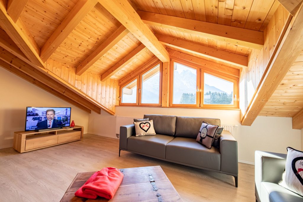 Wohnzimmer mit Sofa und Fernseher in Ferienwohnung in Garmisch-Partenkirchen