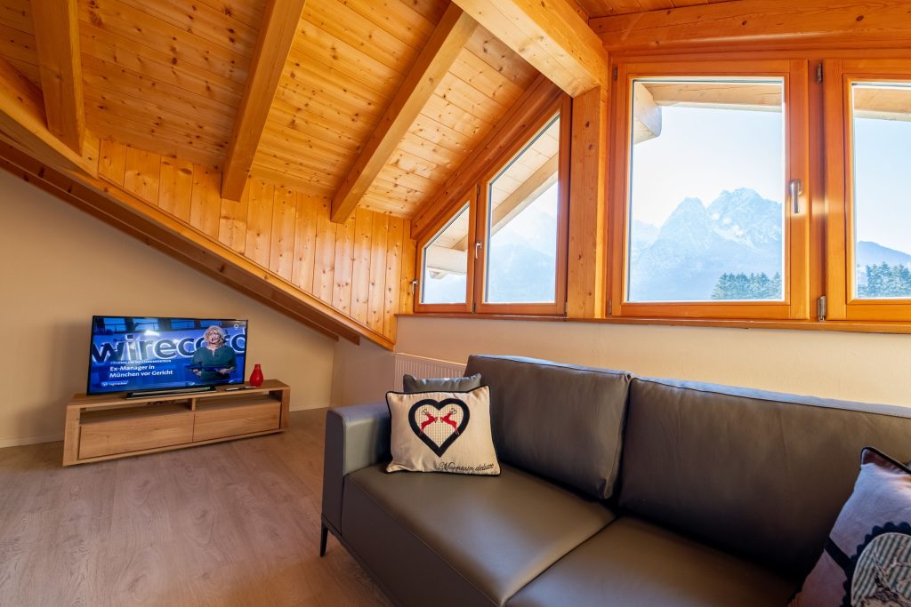 Wohnbereich mit Fernseher und Sofa in Ferienwohnung in Garmisch-Partenkirchen