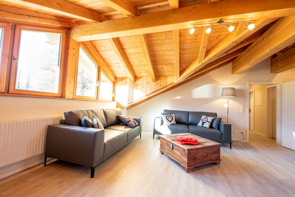 Wohnzimmer mit zwei schwarzen Sofas und einem Holztisch in Ferienwohnung in Garmisch-Partenkirchen