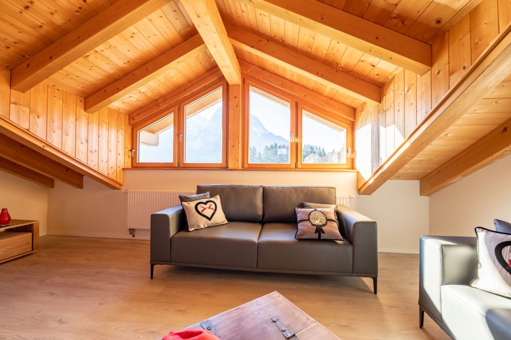 Wohnzimmer mit schwarzem Sofa und Ausblick in Ferienwohnung in Garmisch-Partenkirchen