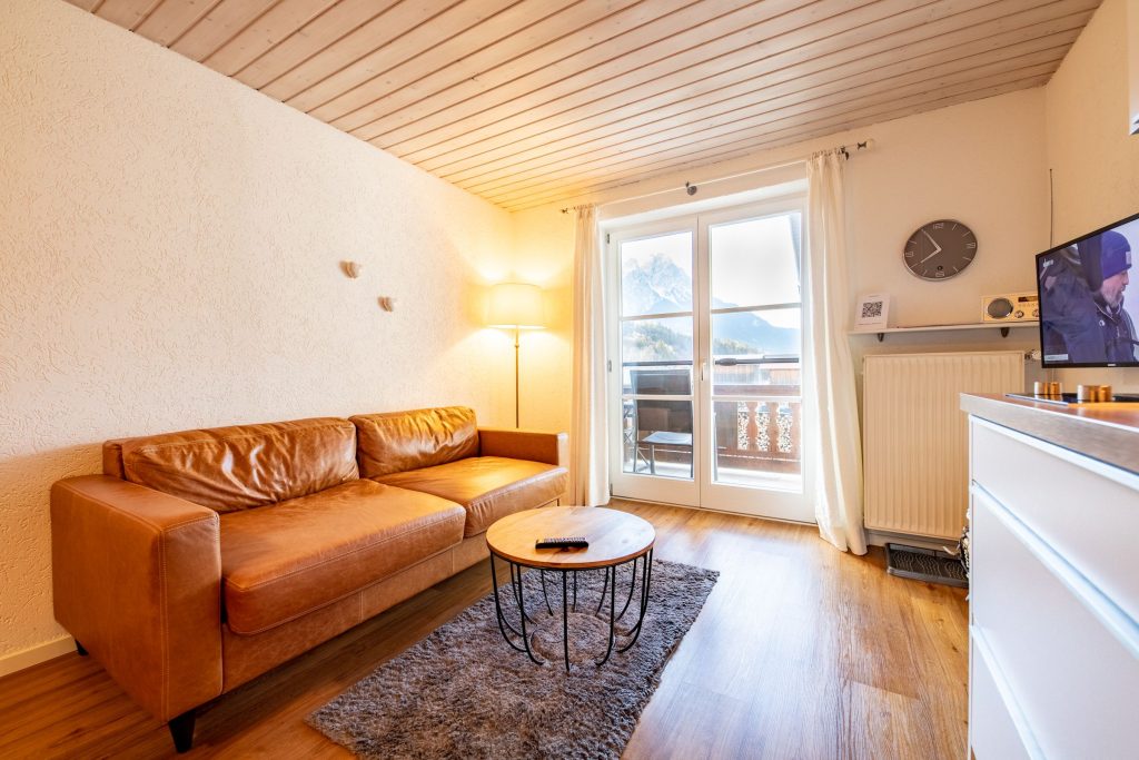 Wohnbereich mit Uhr und Fernseher in Ferienwohnung in Garmisch-Partenkirchen