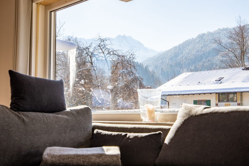 Wohnzimmer mit großem Fenster mit Blick auf die Berge in Ferienwohnung in Garmisch-Partenkirchen