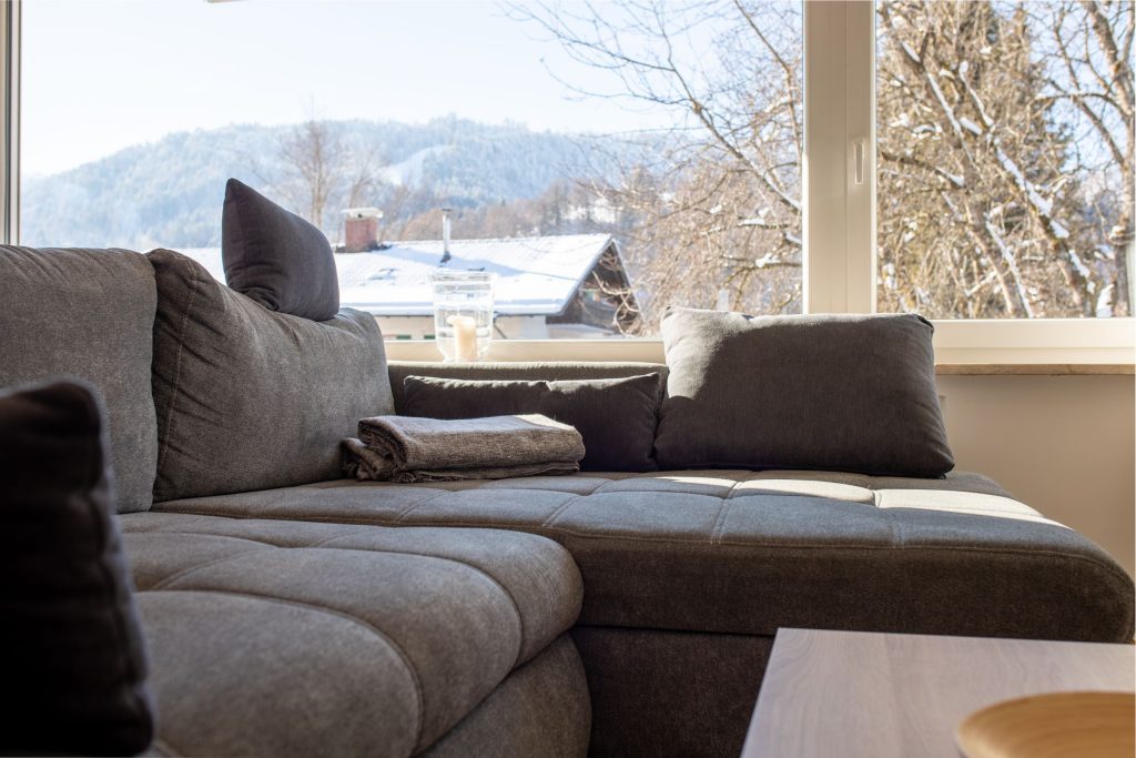 Sofa in grau mit großem Fenster in Ferienwohnung in Garmisch-Partenkirchen