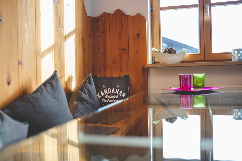 Sitzbank mit Kissen und ein Glastisch  in Ferienwohnung in Garmisch-Partenkirchen