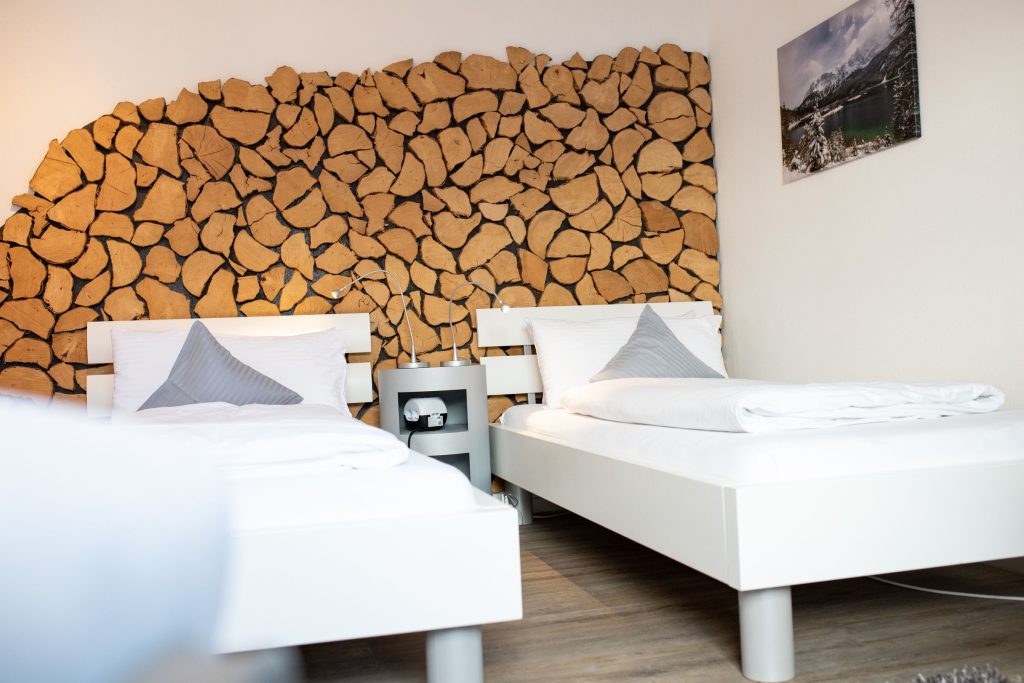 zwei Einzelbetten mit einer Holz gemusterten Wand und einem Landschaftsbild in Ferienwohnung in Garmisch-Partenkirchen