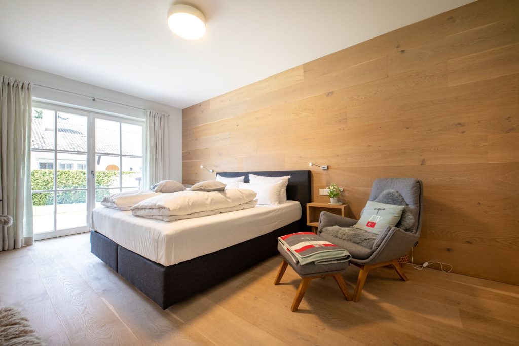 Schlafzimmer mit großer Holzwand und Holzboden in Ferienwohnung in Garmisch-Partenkirchen