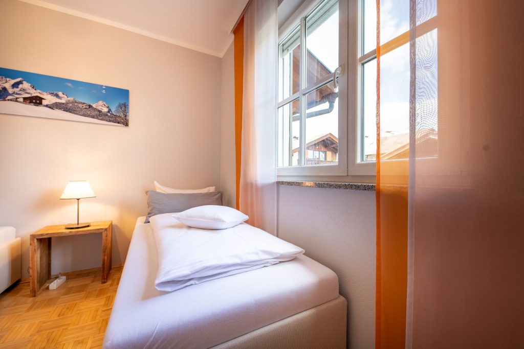 Einzelbett und Fenster in Ferienwohnung in Garmisch-Partenkirchen