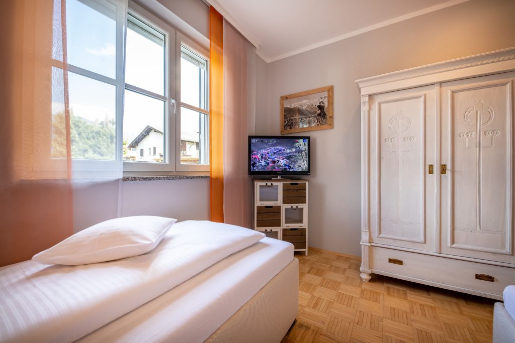 Schlafzimmer mit Fernseher und Schrank in Ferienwohnung in Garmisch-Partenkirchen