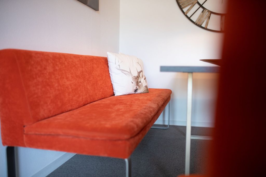 Rotes Sofa mit Hirschkissen in Ferienwohnung in Garmisch-Partenkirchen