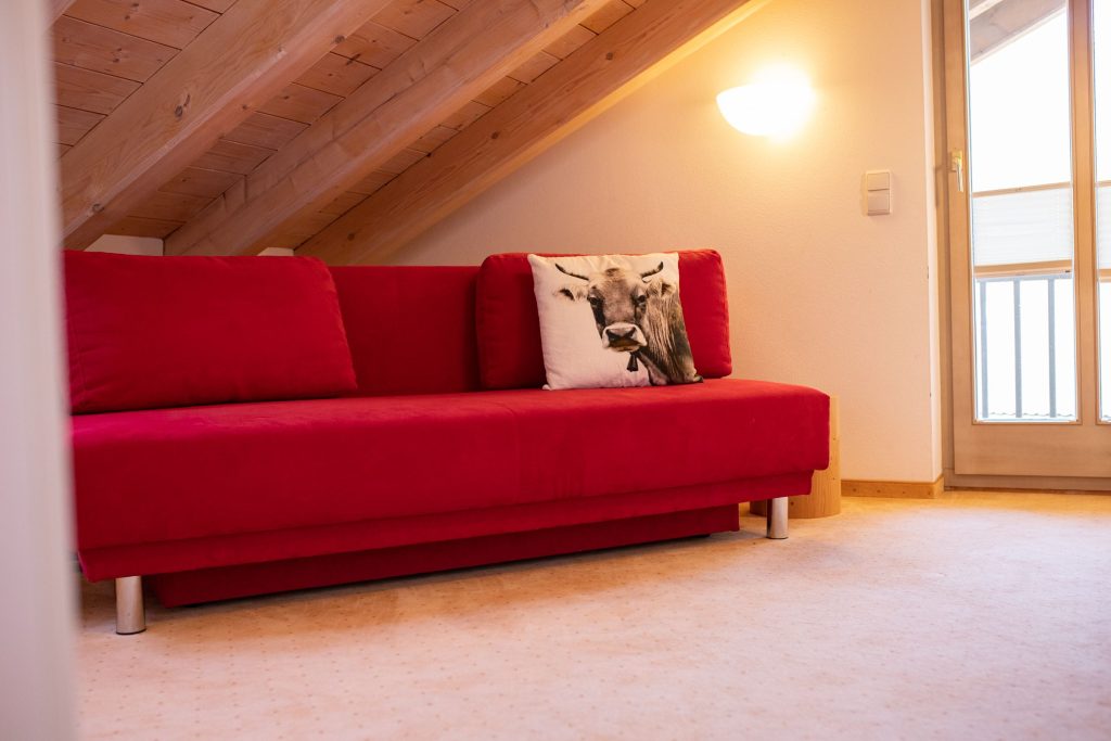 Rotes Sofa mit Kuhkissen in Ferienwohnung in Garmisch-Partenkirchen