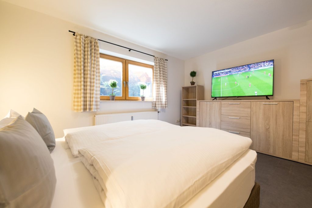 Doppelbett mit großem Fernseher auf Holzschrank in Ferienwohnung in Garmisch-Partenkirchen