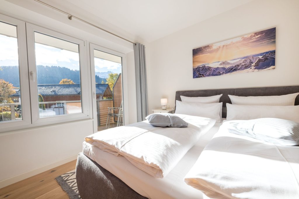 Blick übers Bett zum Fenster hinaus in Ferienwohnung in Garmisch-Partenkirchen