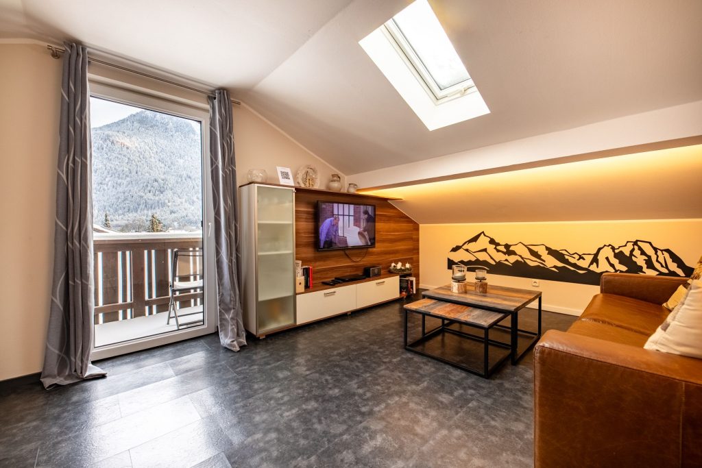 Wohnzimmer mit Fernseher und Dachfenster in Ferienwohnung in Garmisch-Partenkirchen