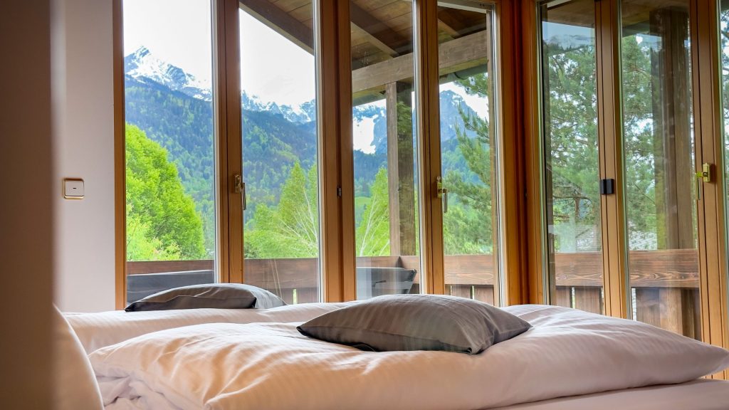 Doppelbett mit großen Fenstern in Ferienwohnung in Garmisch-Partenkirchen