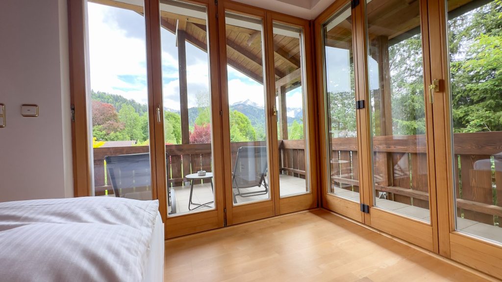 Schlafzimmer mit hohen Fenstern und Balkon in Ferienwohnung in Garmisch-Partenkirchen