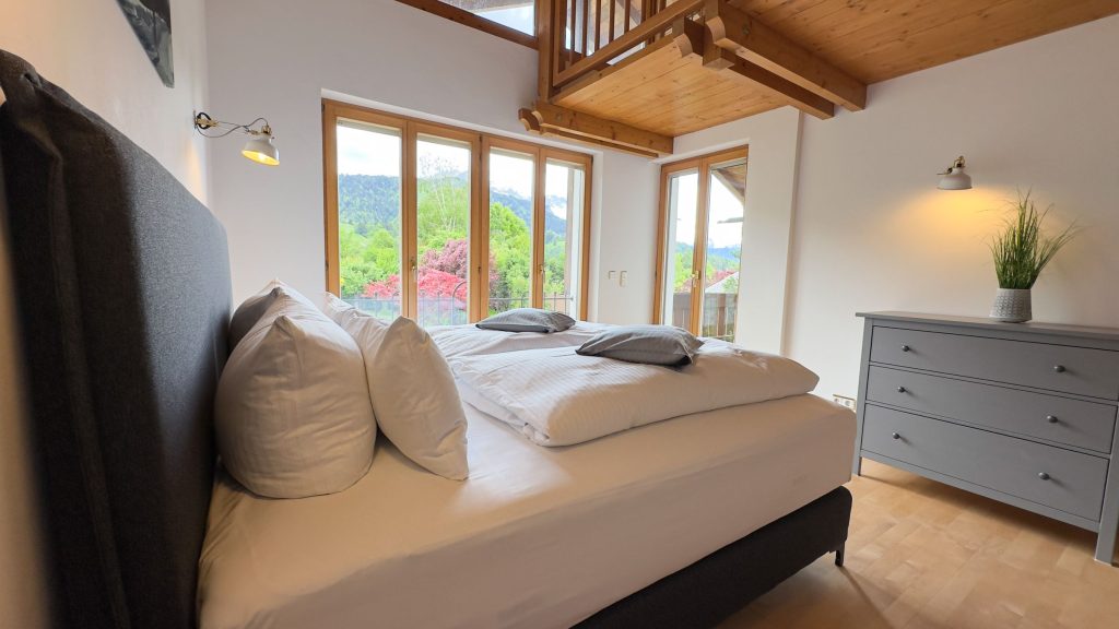 Schlafzimmer mit Doppelbett und großen Fenstern in Ferienwohnung in Garmisch-Partenkirchen