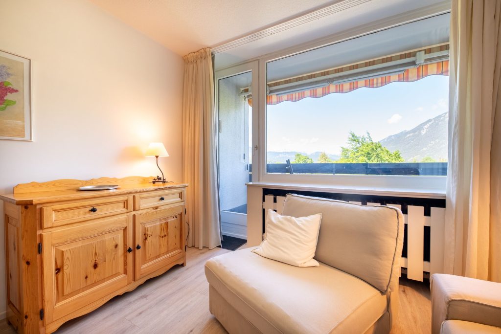 Heller Sessel und Blick zum Fenster in Ferienwohnung in Garmisch-Partenkirchen