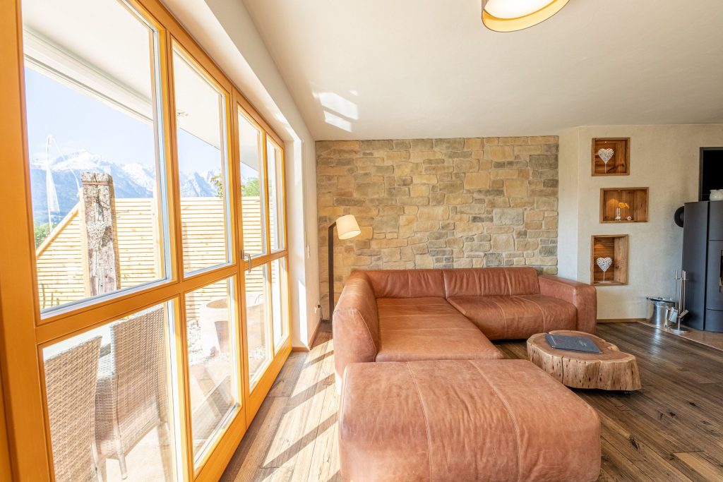 Wohnzimmer mit einer Steinwand und einem braunen Sofa in Ferienwohnung in Garmisch-Partenkirchen