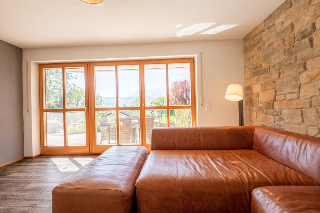 Wohnzimmer mit braunem Sofa und Ausblick auf die Terrasse in Ferienwohnung in Garmisch-Partenkirchen