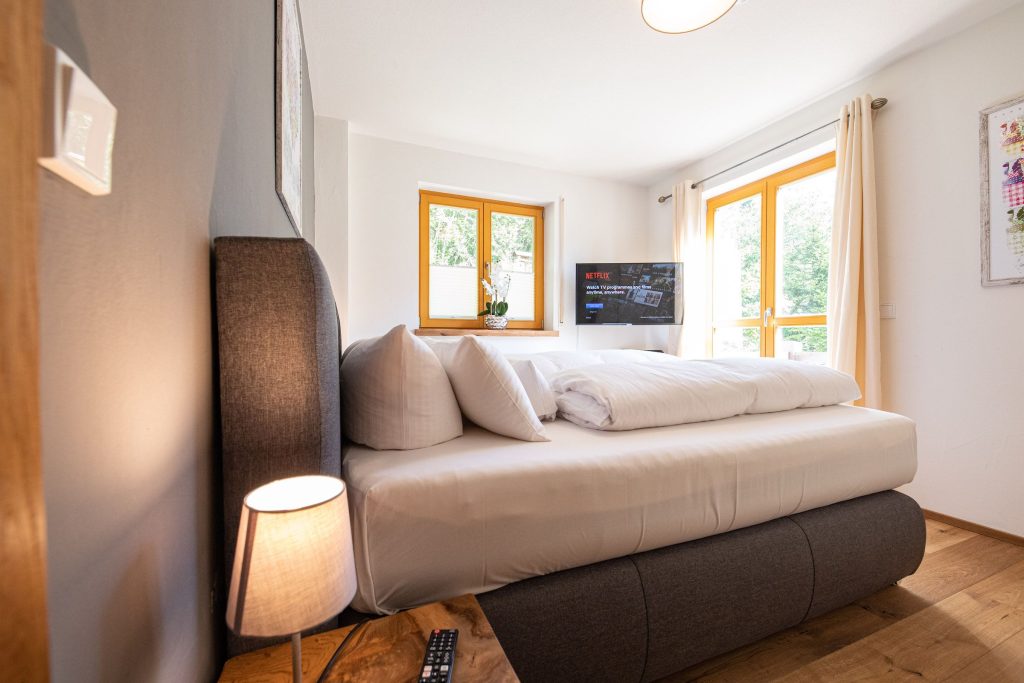 Bett mit Nachtschränkchen und Lampe in Ferienwohnung in Garmisch-Partenkirchen