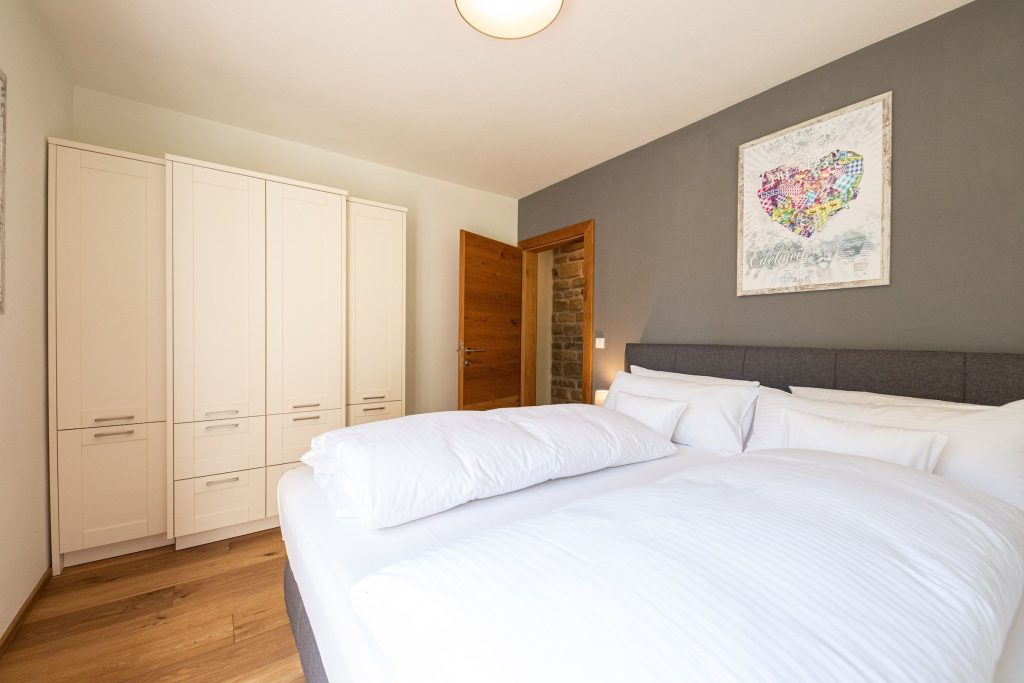 Doppelbett mit einem Kleiderschrank und einem Bild mit Herzform in Ferienwohnung in Garmisch-Partenkirchen