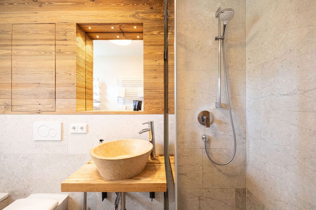 Badezimmer mit Dusche und Waschbecken mit Spiegel in Ferienwohnung in Garmisch-Partenkirchen