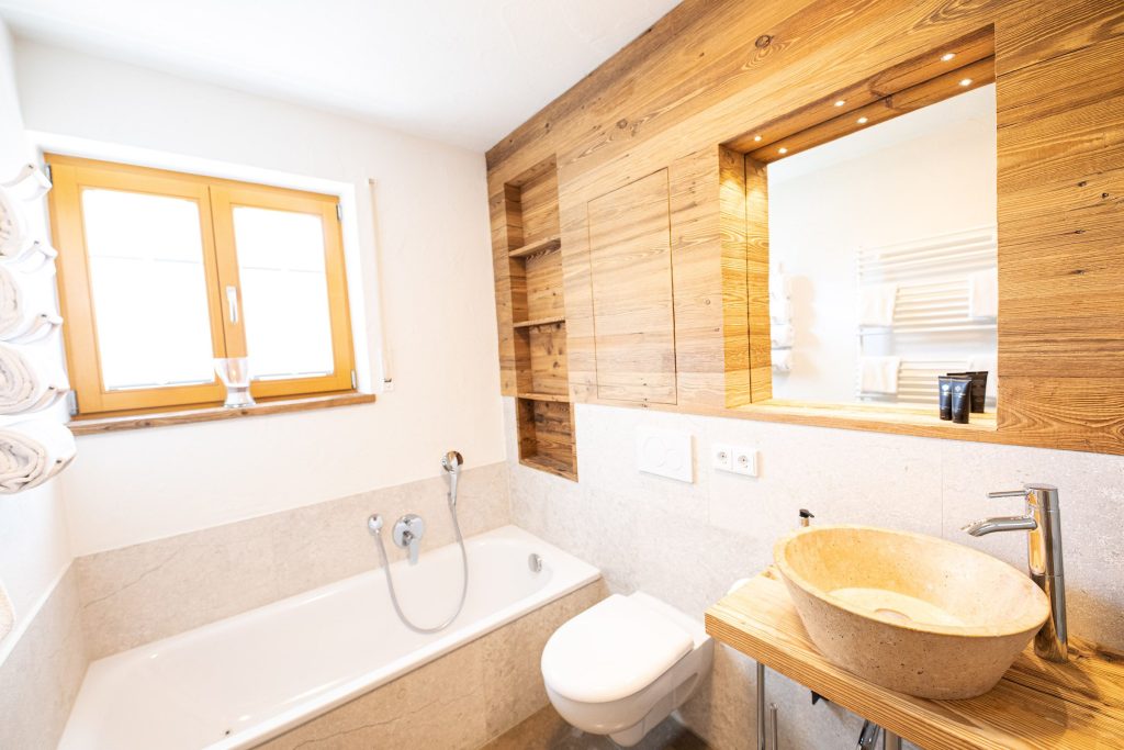 Badezimmer mit Badewanne und Waschbecken mit Spiegel in Ferienwohnung in Garmisch-Partenkirchen