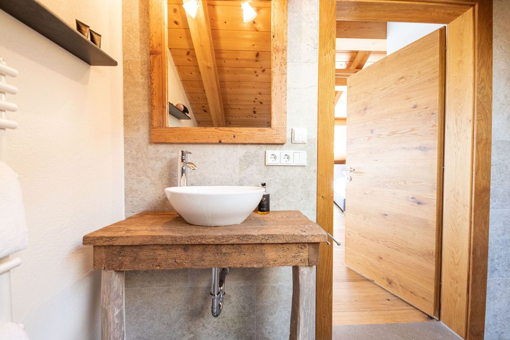 Holztisch mit Waschbecken und einem Spiegel mit Holzrahmen in Ferienwohnung in Garmisch-Partenkirchen