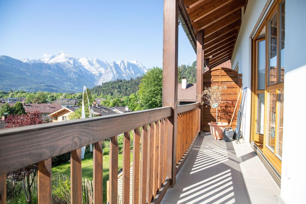 Balkon mit hellgrauen Fliesen und einem Holzzaun in Ferienwohnung in Garmisch-Partenkirchen