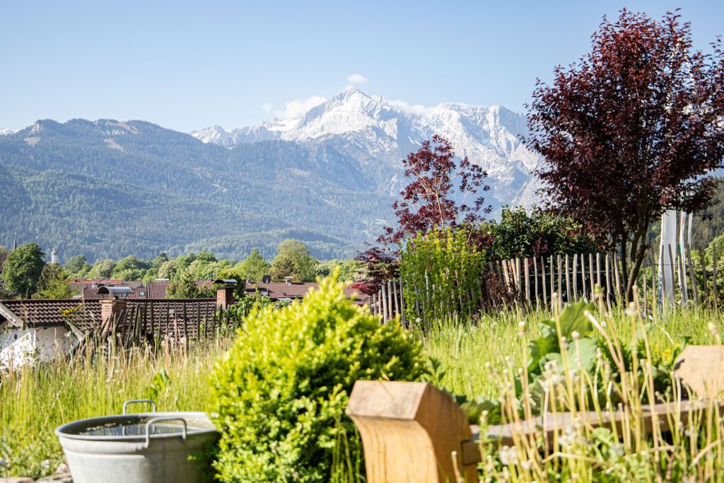 Ausblick auf den grünen Garten und die Alpen in Ferienwohnung in Garmisch-Partenkirchen