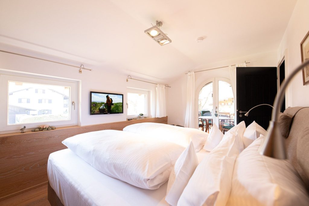 Doppelbett mit Fernseher und Fenster in Ferienwohnung in Garmisch-Partenkirchen