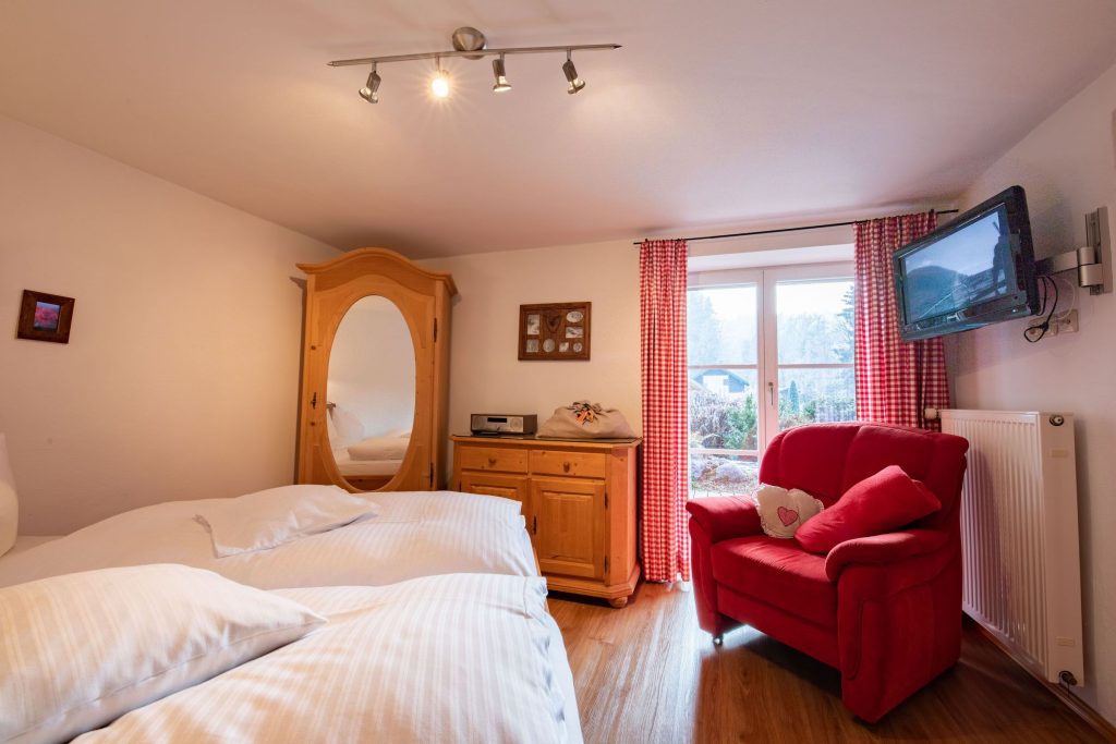 Doppelbett und roter Sessel in Ferienwohnung in Garmisch-Partenkirchen