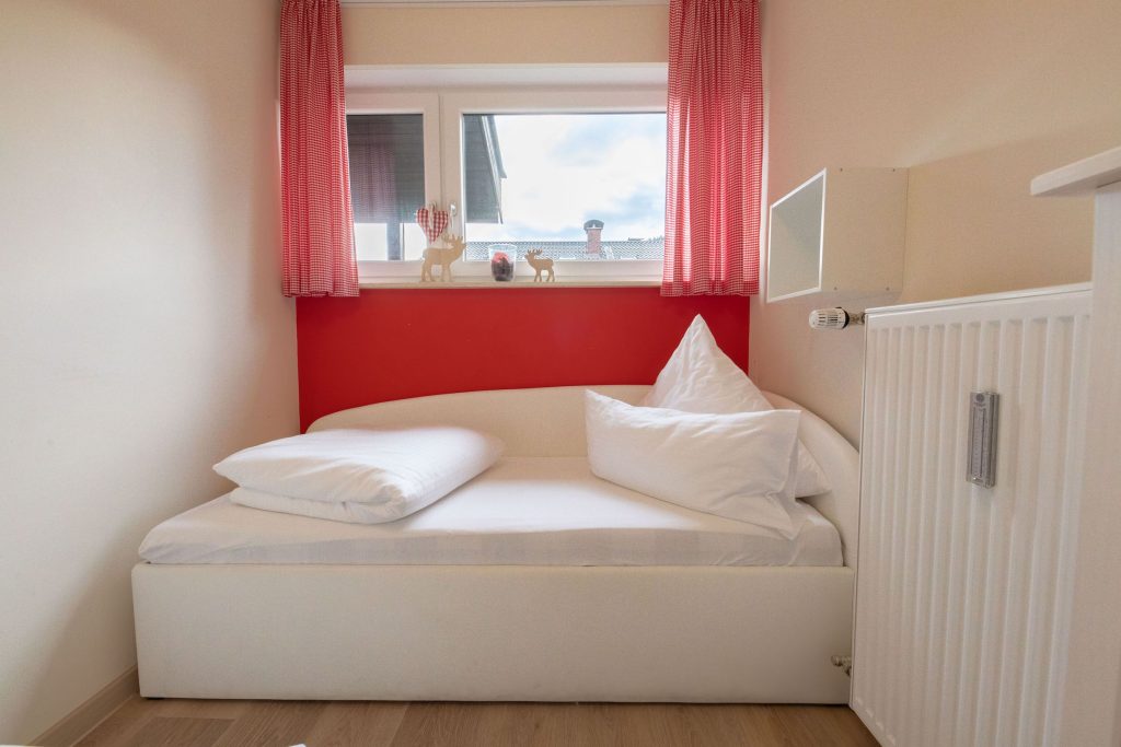 Einzelbett mit roter Wand in Ferienwohnung in Garmisch-Partenkirchen