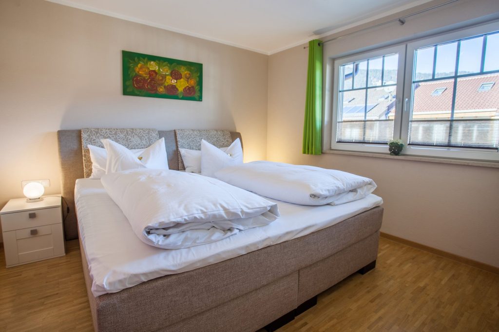 Doppelbett mit grünen Gardienen in Ferienwohnung in Garmisch-Partenkirchen