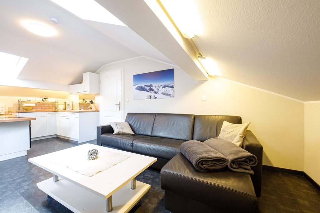 Wohnzimmer mit schwarzem Sofa und weißem Couchtisch in Ferienwohnung in Garmisch-Partenkirchen