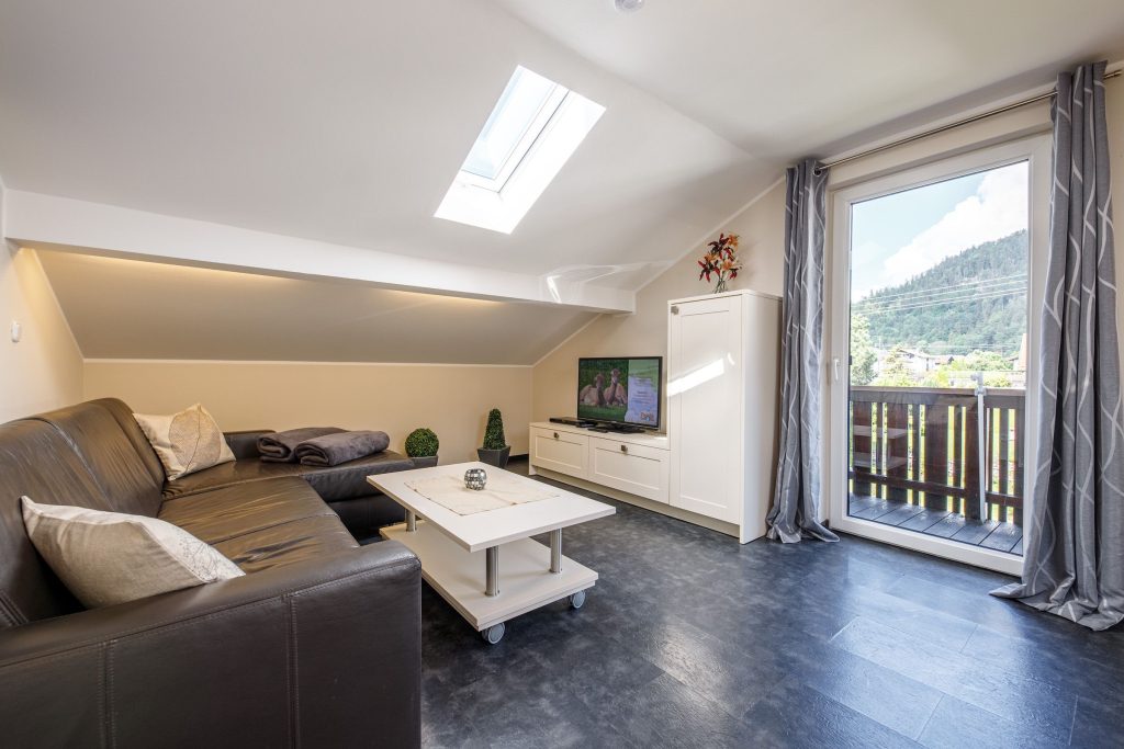 Wohnzimmer mit schwarzem Sofa und Fernseher in Ferienwohnung in Garmisch-Partenkirchen