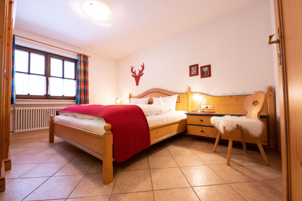 Doppelbett mit Stuhl in Ferienwohnung in Garmisch-Partenkirchen