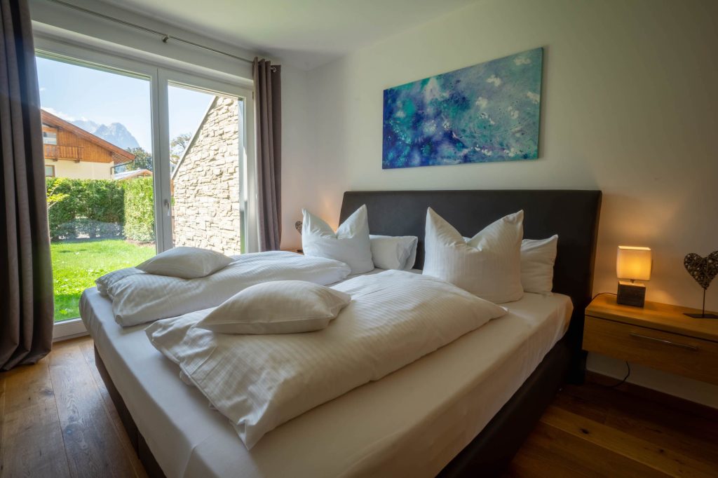 Doppelbett mit Nachttischlampe in Ferienwohnung in Garmisch-Partenkirchen