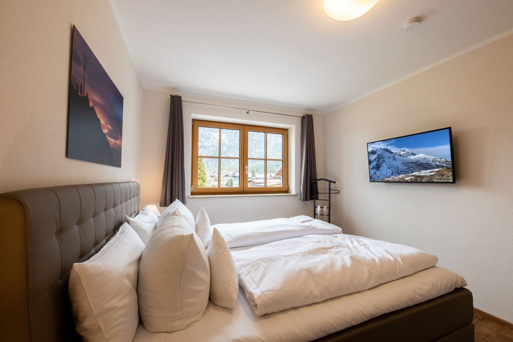 Doppelbett in grau mit Fernseher in Ferienwohnung in Garmisch-Partenkirchen