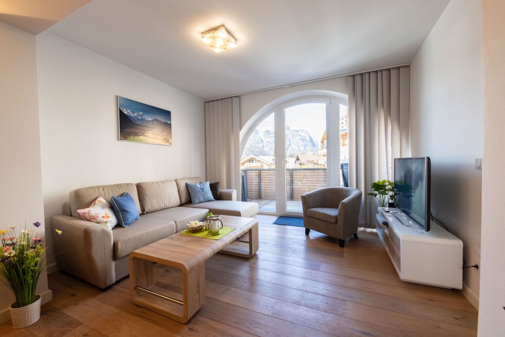 Wohnzimmer mit einem weißen Sideboard mit Fernseher in Ferienwohnung in Garmisch-Partenkirchen