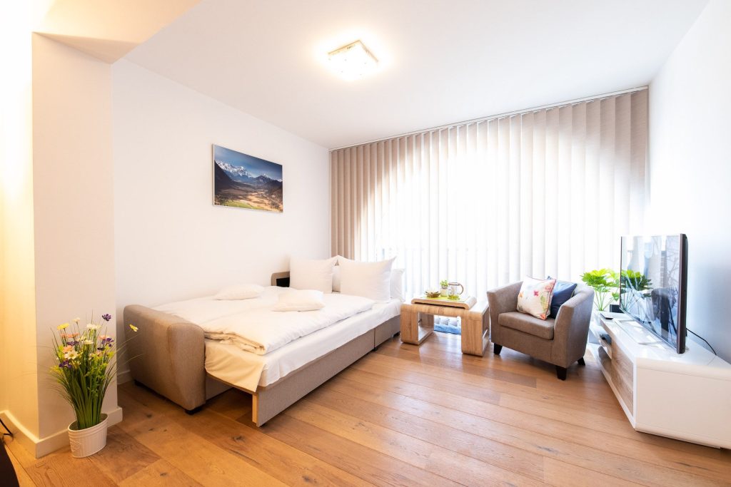 Schlafsofa und ein Sessel mit Fernseher auf einem Sideboard in Ferienwohnung in Garmisch-Partenkirchen