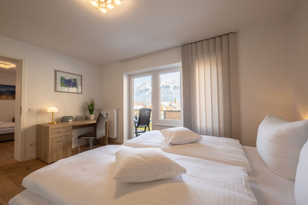 geräumiges Schlafzimmer mit einem Doppelbett und Schreibtisch, außerdem mit einem tollen Ausblick in Ferienwohnung in Garmisch-Partenkirchen