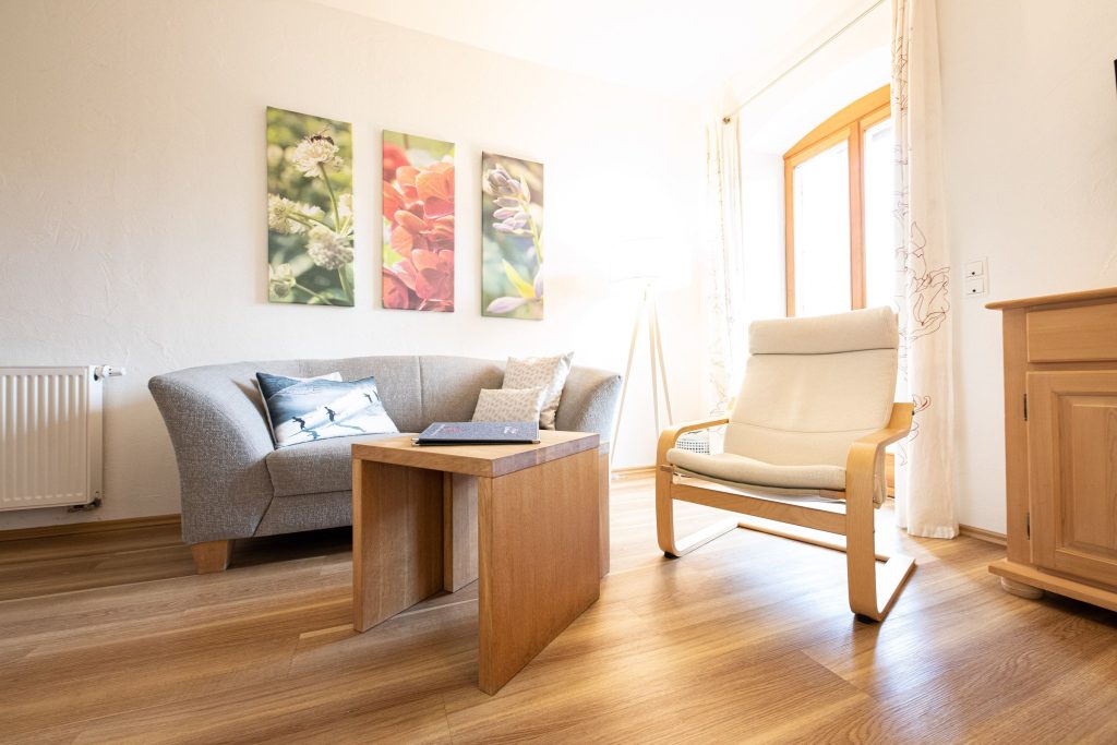 Wohnzimmer mit kleinem Sofa und Stuhl in Ferienwohnung in Garmisch-Partenkirchen