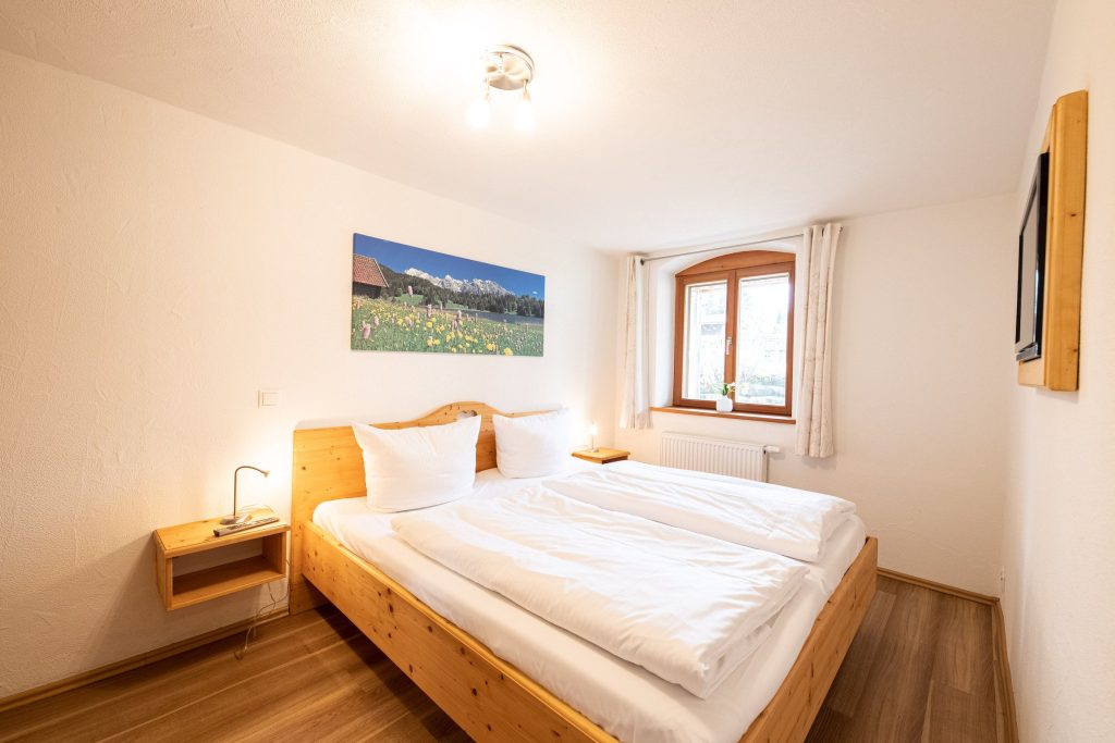 Doppelbett mit Nachttisch und Bild in Ferienwohnung in Garmisch-Partenkirchen