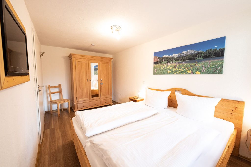 Doppelbettzimmer mit Kleiderschrank und Bild von einer Wiese in Ferienwohnung in Garmisch-Partenkirchen