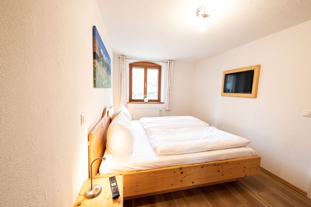 Doppelbettzimmer mit Fernseher und Fenster in Ferienwohnung in Garmisch-Partenkirchen