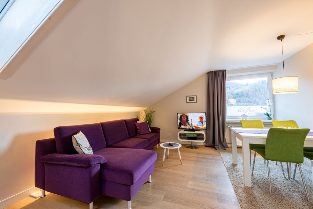 Wohnzimmer mit Lila Sofa und grünen Stühlen in Ferienwohnung in Garmisch-Partenkirchen