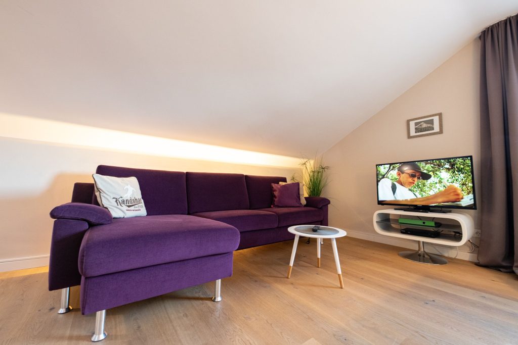 Sofa mit Fernseher und kleinem Tisch in Ferienwohnung in Garmisch-Partenkirchen