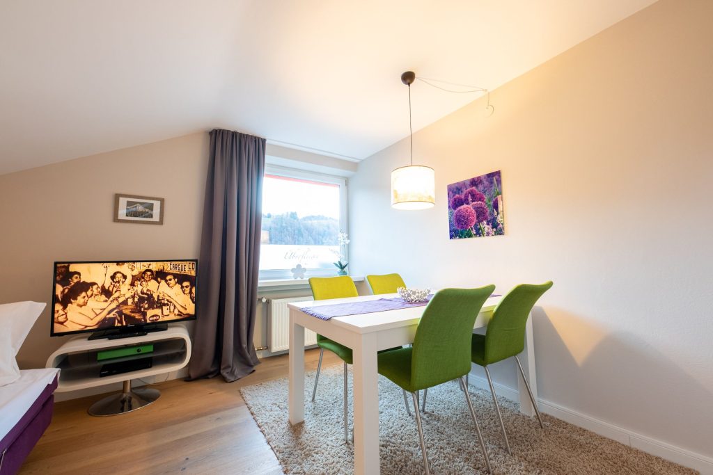 Essbereich mit Fernseher und Blumenbild in Ferienwohnung in Garmisch-Partenkirchen